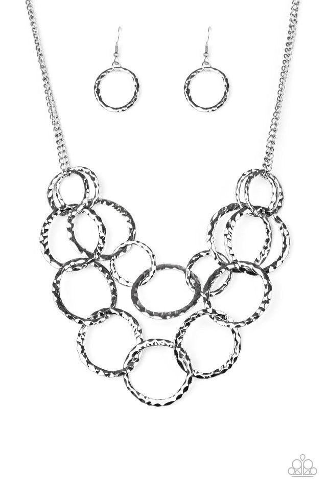 Paparazzi Accessories Radiant Ringmaster - Black Varying in size, gunmetal rings are delicately hammered with light catching shimmer. The glistening rings link below the collar, draping into two layered rows for an edgy finish. Features an adjustable clas