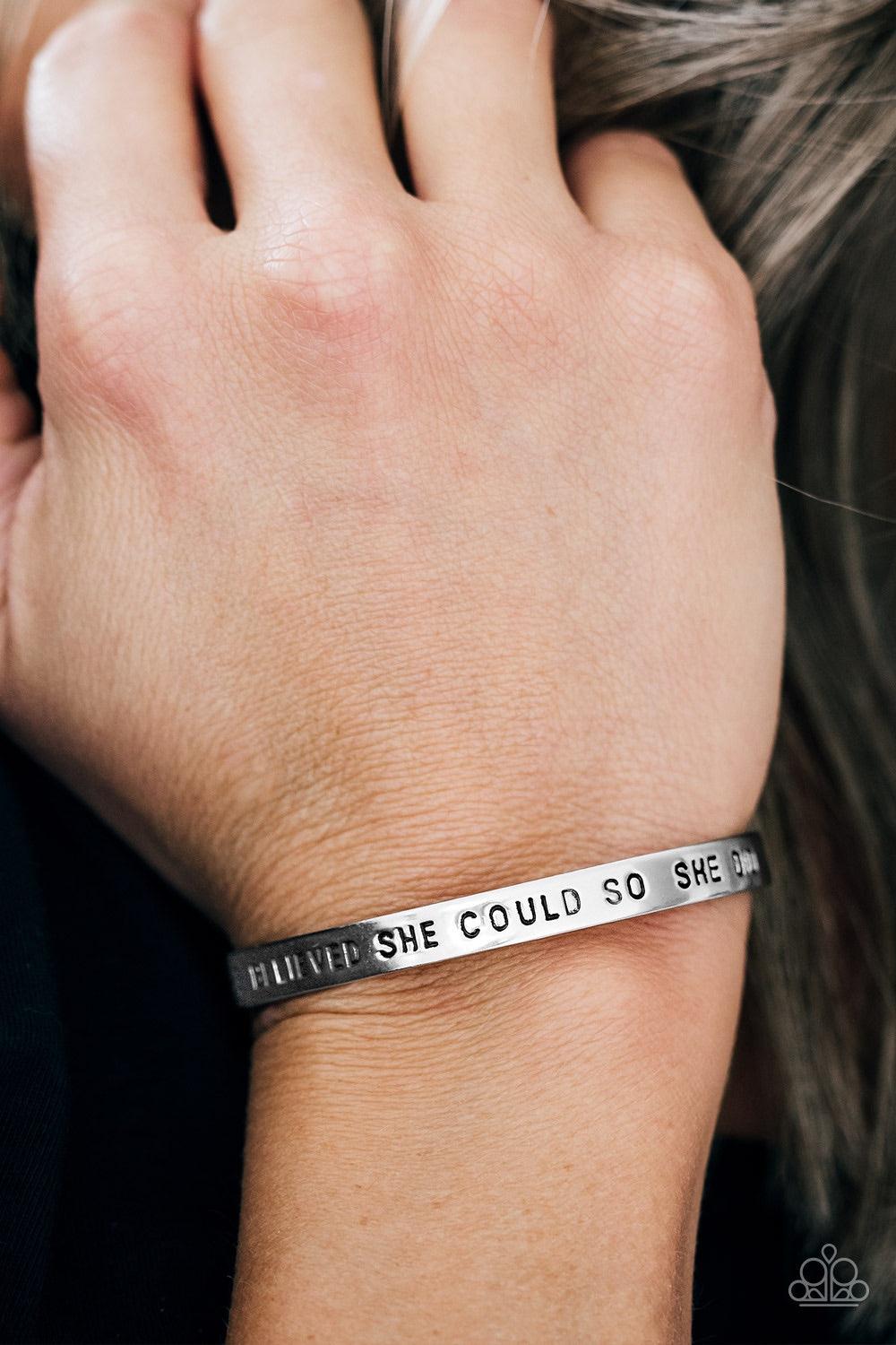 Paparazzi Accessories She Believed She Could - Silver A silver cuff wraps around the wrist in a bright and casual fashion. Painted in a black hue, the phrase “She believed she could so she did” runs horizontally across the cuff for an inspirational finish