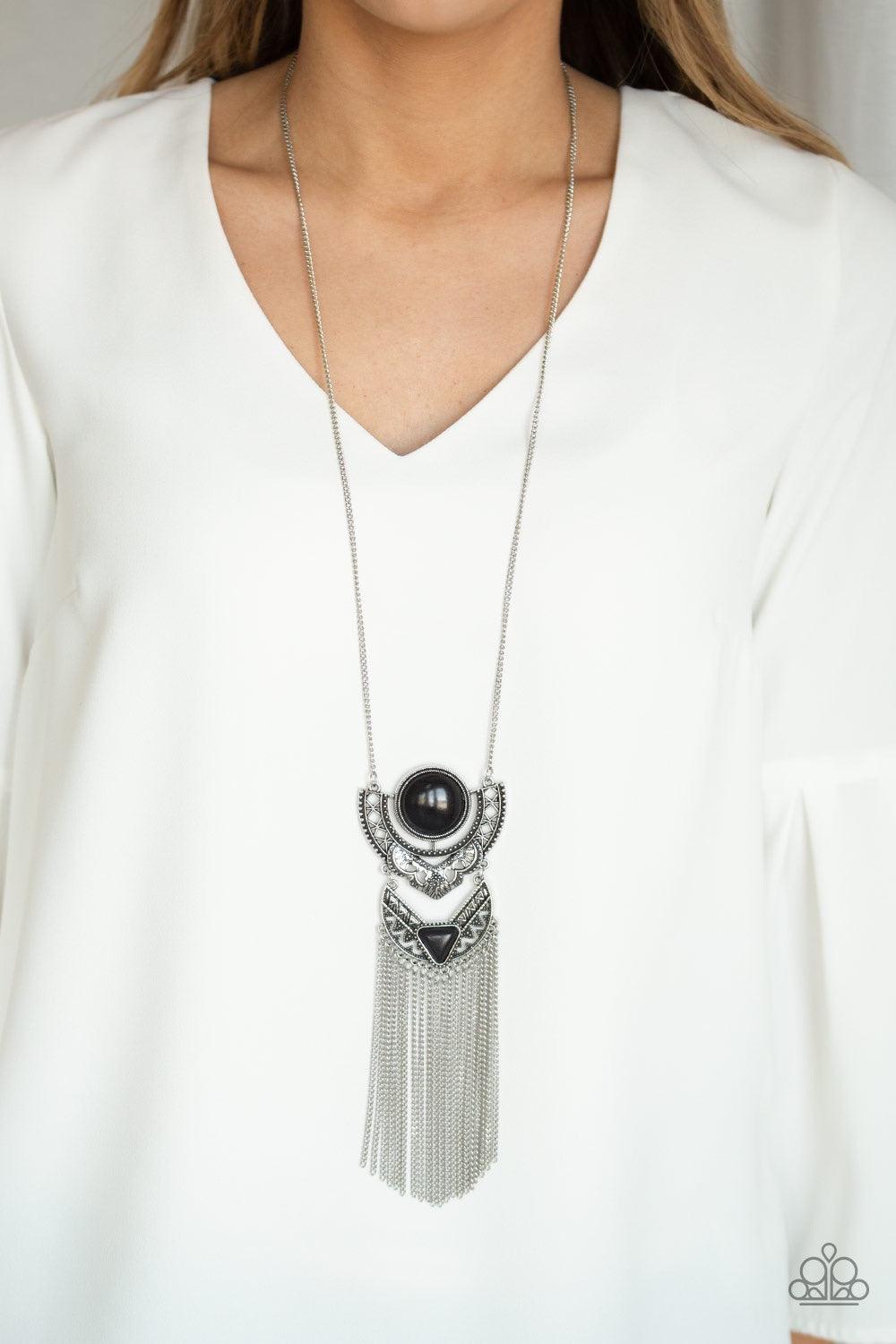 Paparazzi Accessories Spirit Trek - Black Featuring earthy black stone accents, ornate silver plates link at the bottom of a lengthened silver chain for a dramatic tribal look. Shimmery silver chains stream from the bottom of the stacked pendant, adding a