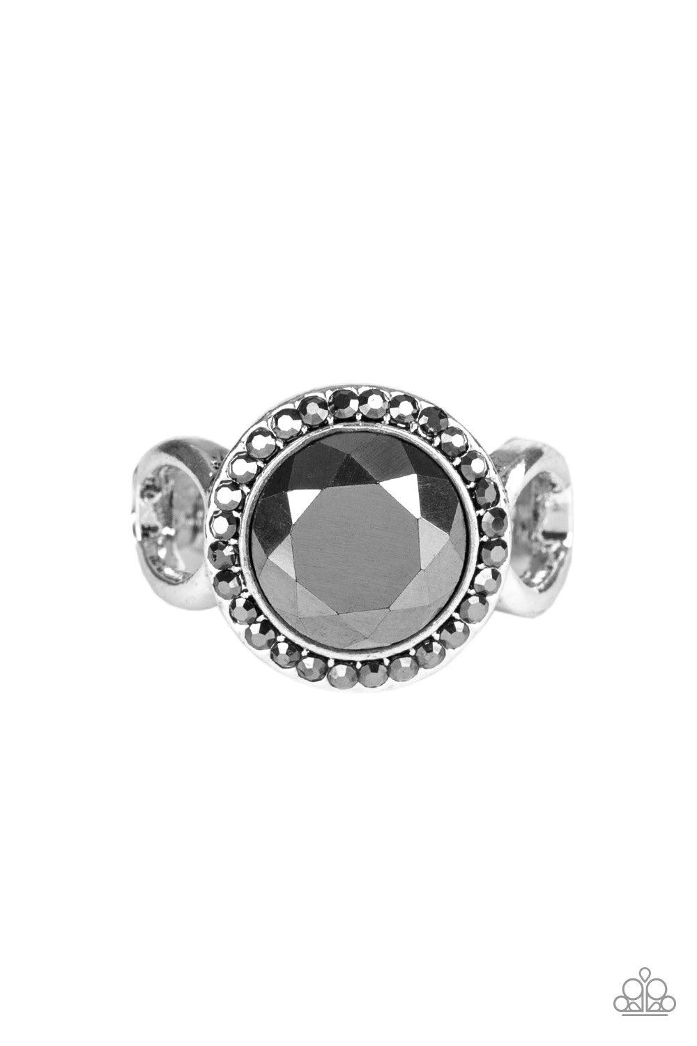 Paparazzi Accessories It’s Gonna GLOW! - Black An oversized hematite gem is pressed into the center of a round silver frame encrusted in a ring of radiant hematite rhinestones for a regal flair. Features a dainty stretchy band for a flexible fit. Jewelry