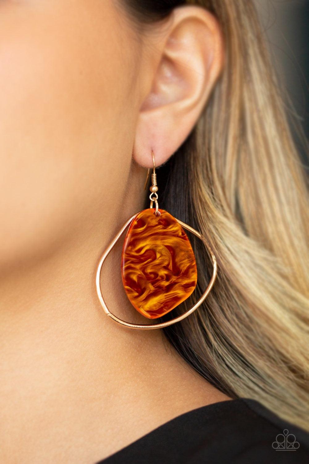 Paparazzi Accessories HAUTE Toddy - Orange Brushed in an orange shell-like iridescence, an abstract acrylic frame swings from the top of an asymmetrical gold hoop for a seasonal flair. Earring attaches to a standard fishhook fitting. Jewelry