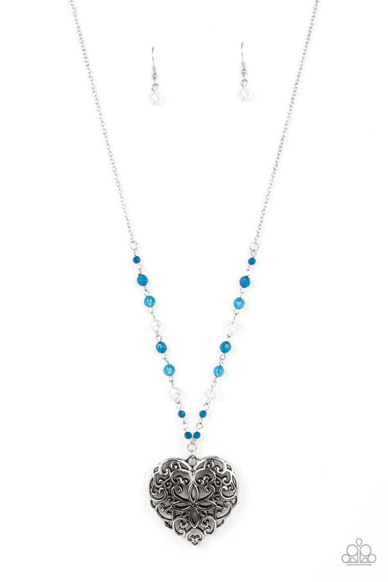 Paparazzi Accessories Doting Devotion - Blue Featuring opaque and glassy crystal-like finishes, a dainty collection of Mykonos Blue and white beads gives way to an oversized filigree filled heart frame, creating an antiqued locket inspired pendant at the