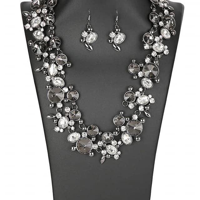 Paparazzi Accessories Phenomenon Encased in shimmery metallic frames, clusters of glassy white rhinestones and mysterious smoky gems in a range of sizes and shapes wrap dramatically around the collar in a show-stopping finish. Sleek gunmetal accents are s