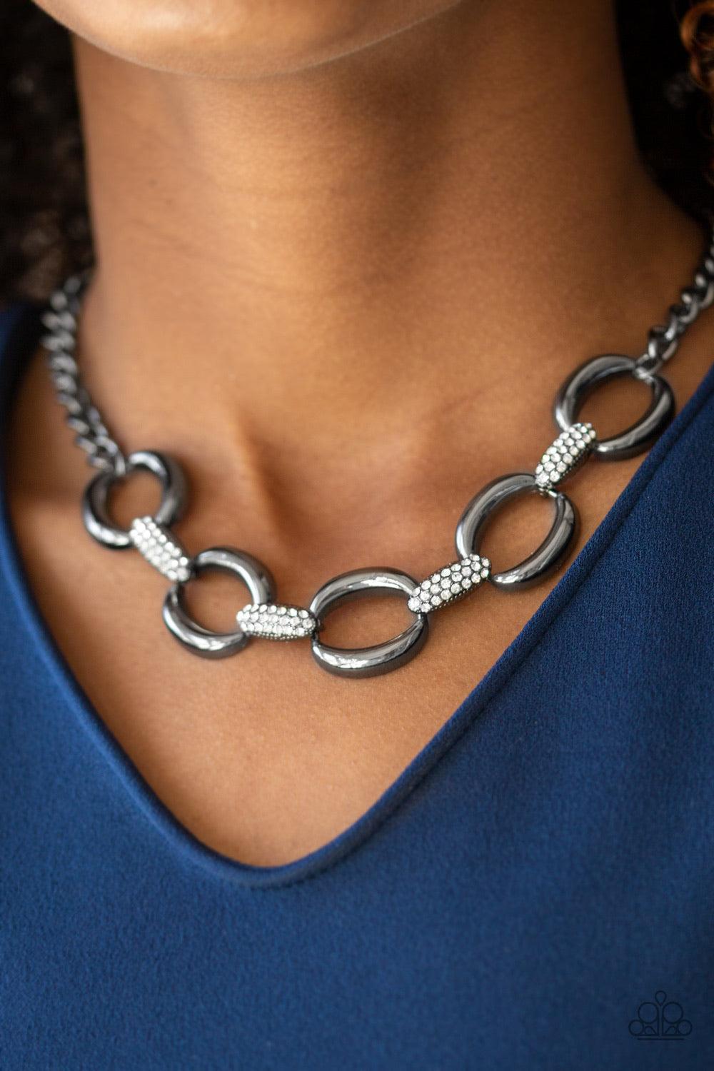 Paparazzi Accessories Boss Boulevard - Black Bold gunmetal links join with white rhinestone encrusted frames below the collar for a fierce look. Features an adjustable clasp closure. Sold as one individual necklace. Includes one pair of matching earrings.