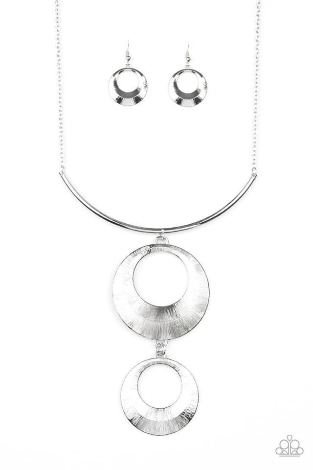 Paparazzi Accessories Egyptian Eclipse - Silver Featuring a blinding scratch finish, two beveled silver circular frames swing from the bottom of a bowing silver rod, creating an edgy stacked pendant down the chest. Features an adjustable clasp closure. Je