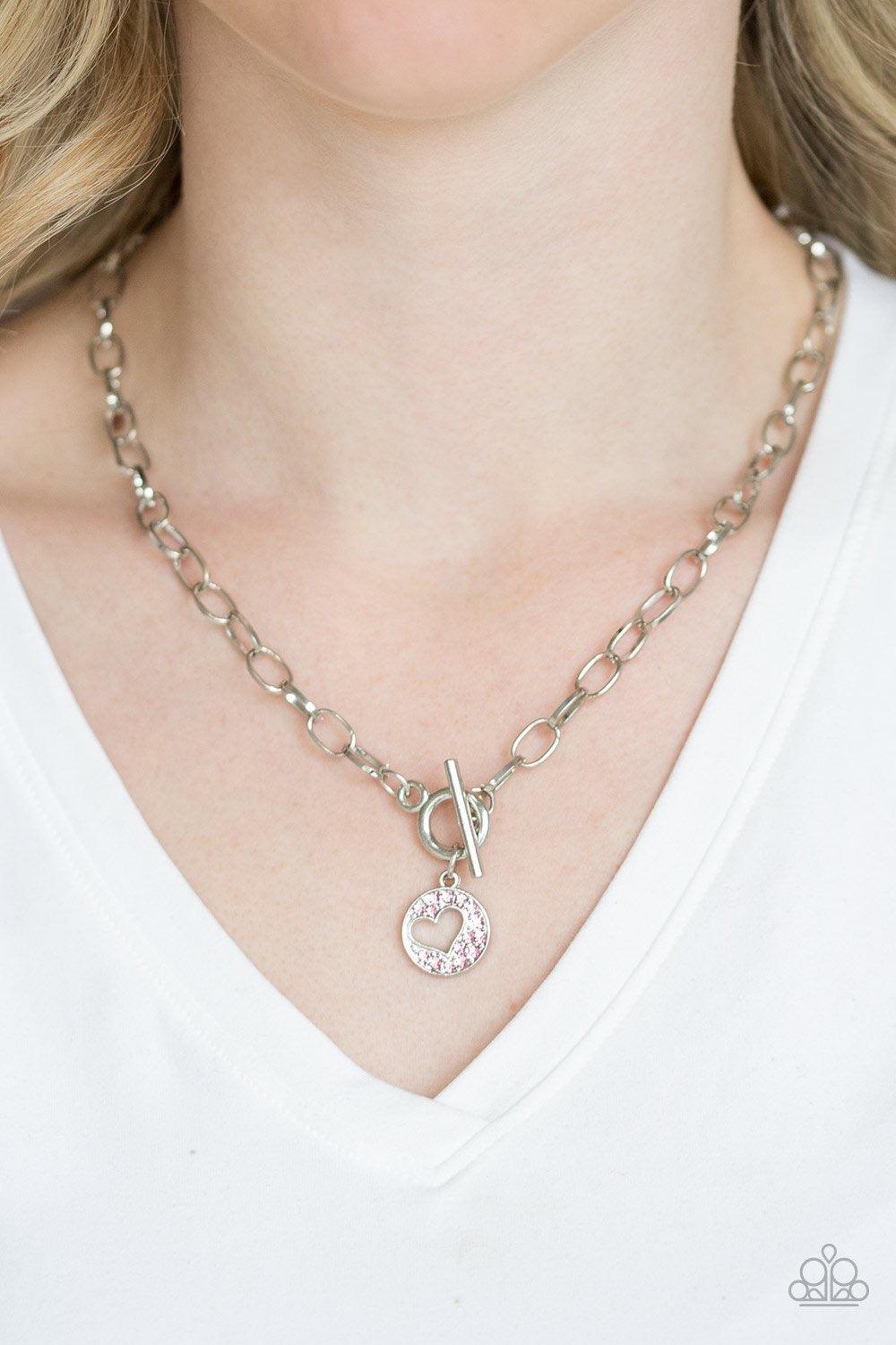 Paparazzi Accessories Heartbeat Retreat - Pink Radiating with glittery pink rhinestones, an airy heart pendant swings from the bottom of a glistening silver chain below the collar for a flirty flair. Features a toggle clasp. Sold as one individual necklac