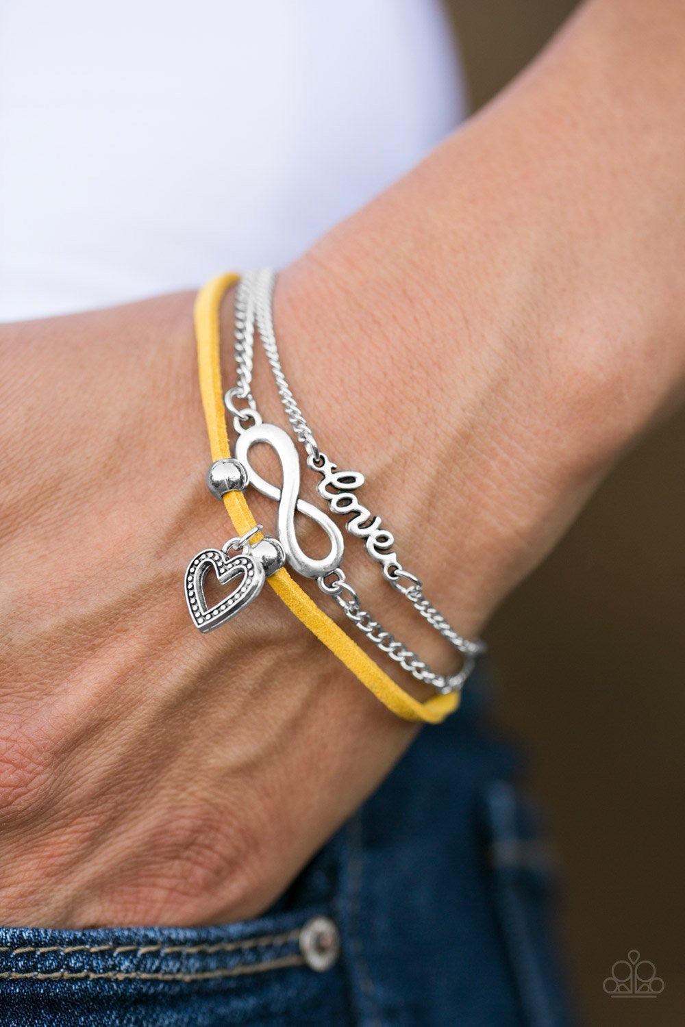 Paparazzi Accessories Laguna Love - Yellow A strip of skinny yellow suede joins two shimmery silver chains around the wrist, creating colorful layers. A dainty heart, infinity, and silver charm spelling out "love" across the wrist, adorn the layered palet
