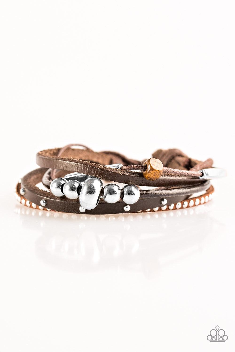 Paparazzi Accessories Long Road Home - Brown A mishmash of skinny leather bands and shiny brown cording layer across the wrist. Featuring mismatched studded textures and shiny metallic accents, a single wooden bead slides along the brown cord for an urban