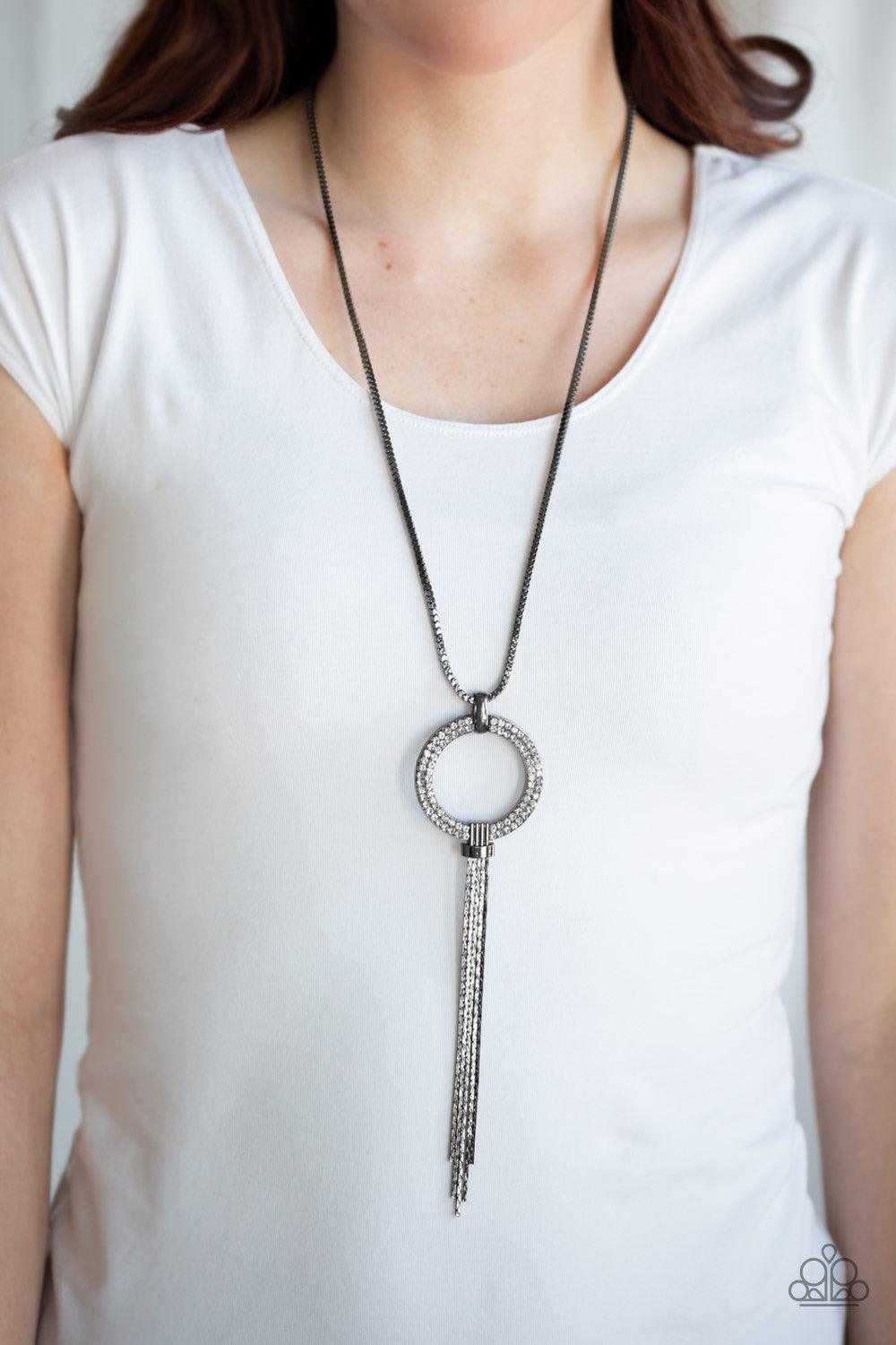 Paparazzi Accessories Not A HEIR Out Of Place - Black Encrusted in blinding white rhinestones, a sparkling gunmetal ring swings from the bottom of a lengthened gunmetal box chain. Flattened gunmetal chains stream from the bottom of the glittery pendant fo