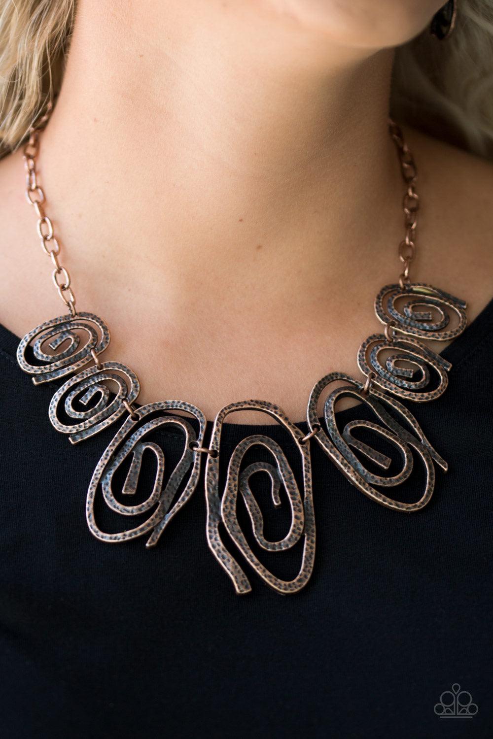 Paparazzi Accessories My Cave is Your Cave - Copper Delicately hammered in shimmery detail, warped copper frames spin into dizzying spirals. Gradually increasing in size near the center, the asymmetrical frames link below the collar for a bold tribal insp