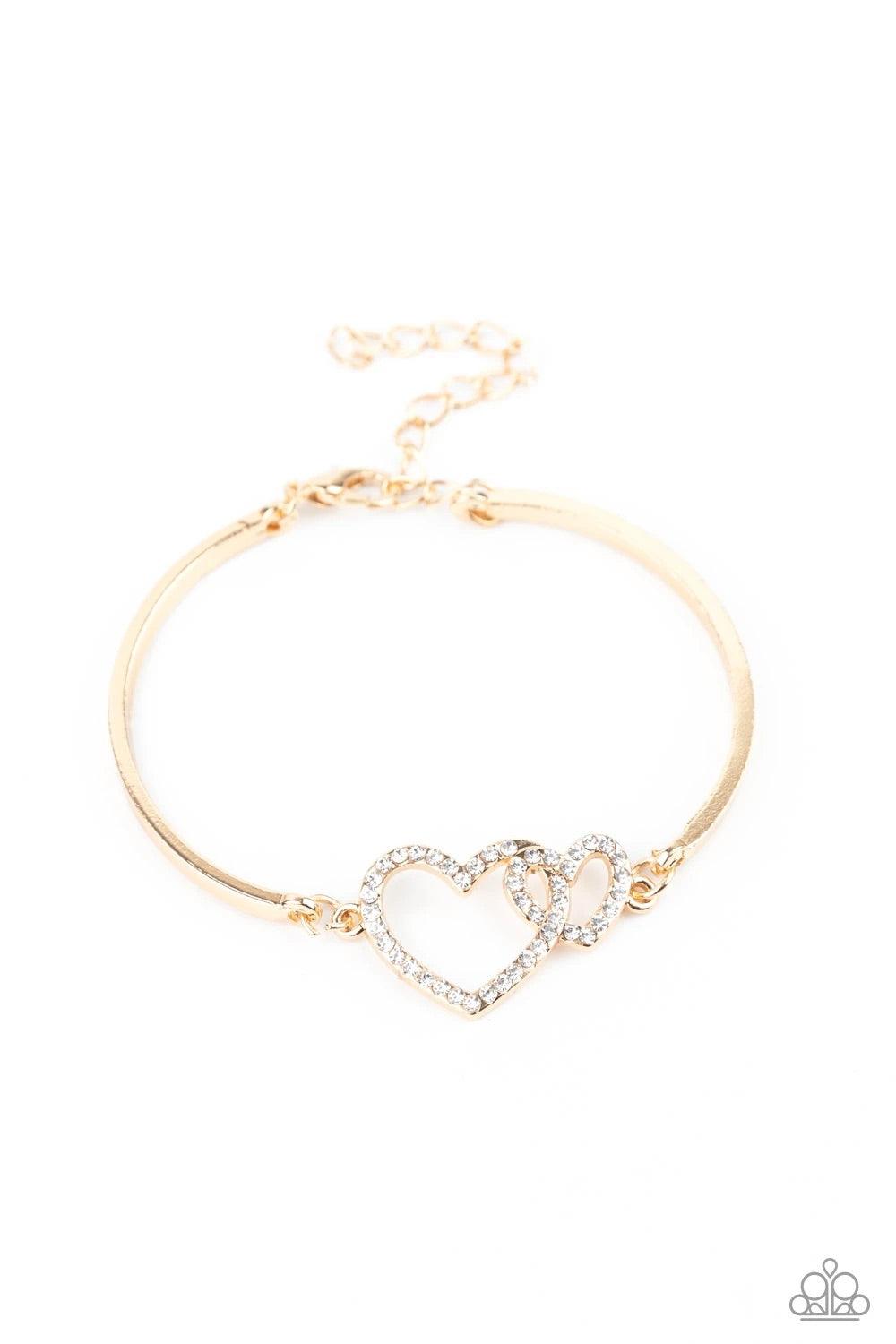Paparazzi Accessories Cupid is Calling - Gold Encrusted in dainty white rhinestones, a charming pair of interlocking heart frames attach to two gold bars around the wrist, creating a flirty bangle-like bracelet. Features an adjustable clasp closure. Sold