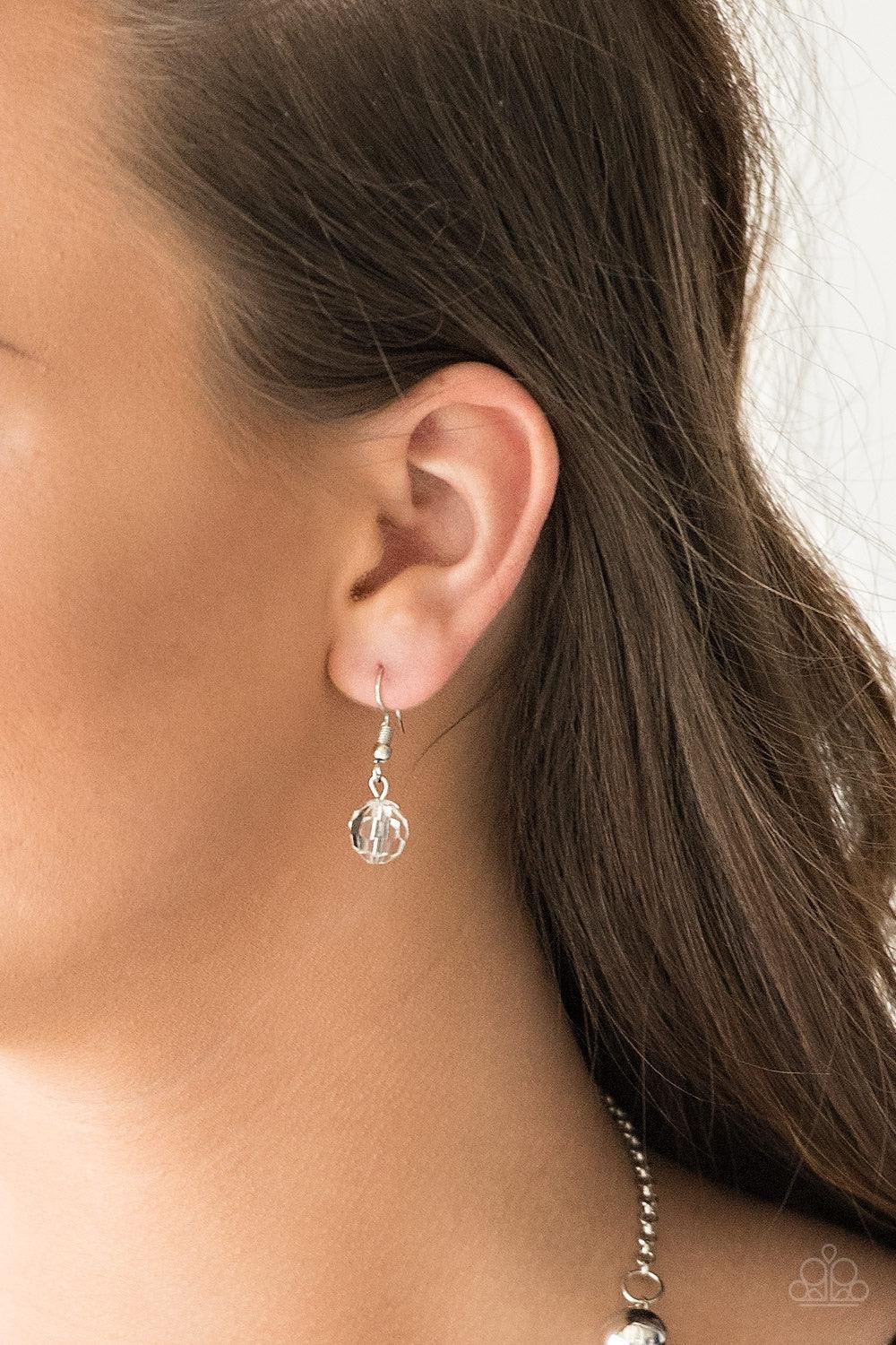 Paparazzi Accessories Luminous Luminary - White A dainty white rhinestone encrusted heart frame swings from the top of an oversized silver heart frame, creating a charming duo. Earring attaches to a standard fishhook fitting. Jewelry