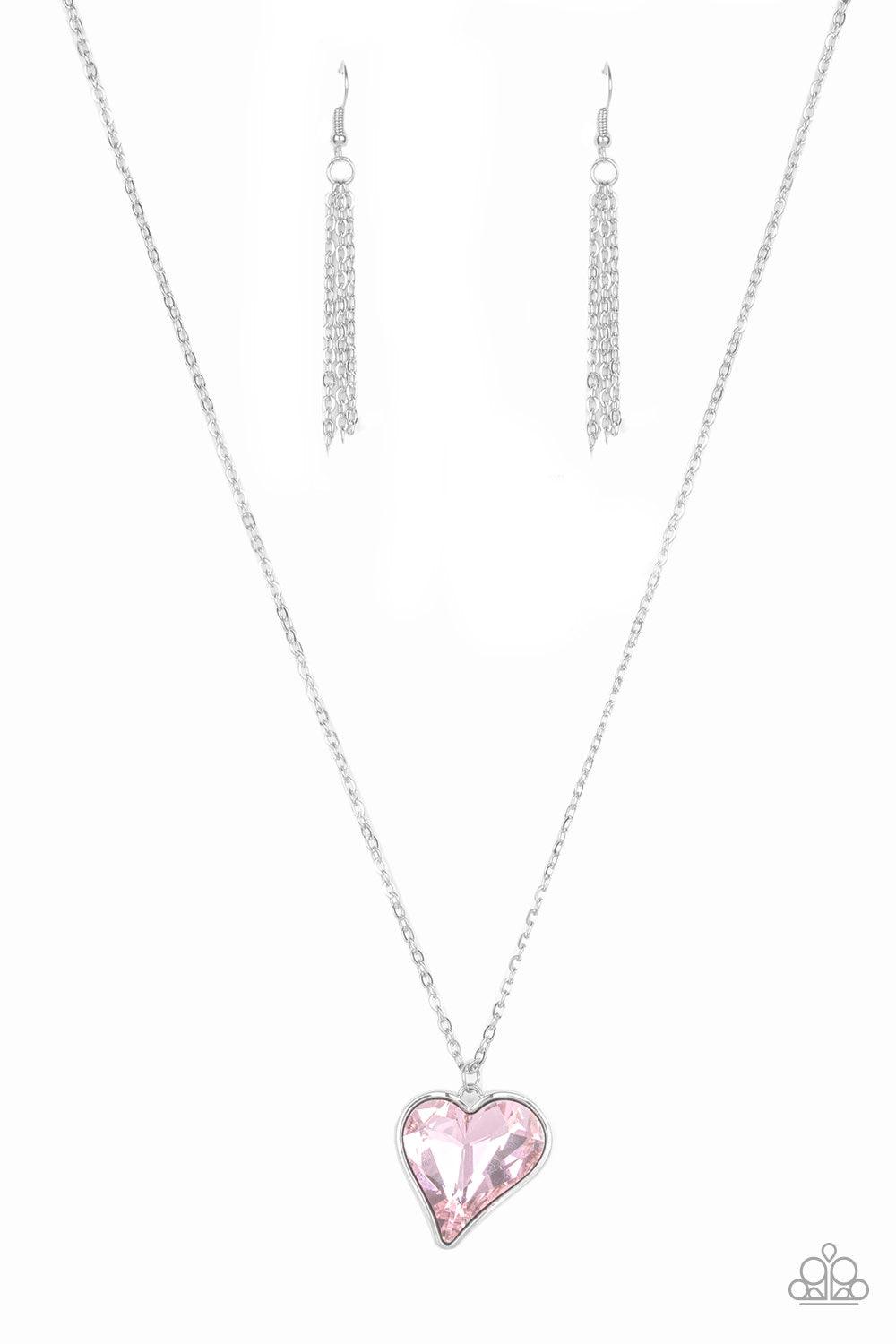Paparazzi Accessories Heart Flutter - Pink Chiseled into a charming heart, an oversized pink rhinestone gem is nestled inside a sleek silver frame, creating a flirtatious pendant below the collar. Features an adjustable clasp closure. Jewelry