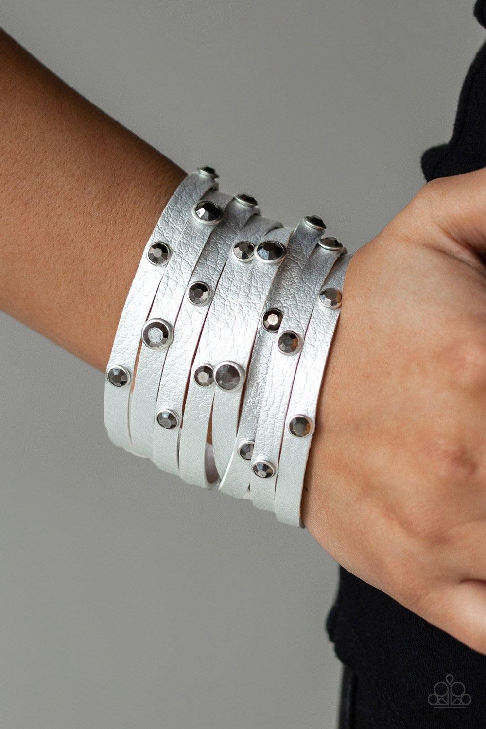 Paparazzi Accessories Go-Getter Glamorous - Silver Brushed in a metallic shimmer, a thick gray leather band has been spliced into eight strips across the wrist. Encased in sleek silver fittings, glittery hematite rhinestones are sprinkled across the cente