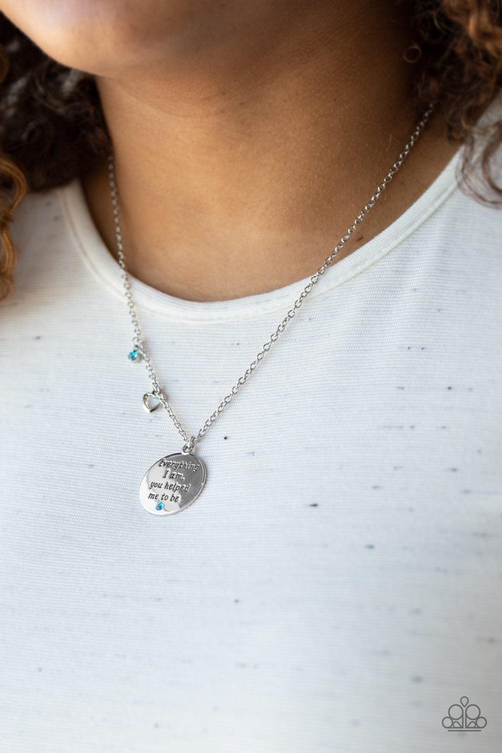Paparazzi Accessories Everything I Am - Blue A solitaire blue rhinestone, dainty silver heart, and a shimmery silver disc stamped with the inspirational phrase, "Everything I am, you helped me be", swings below the collar for a whimsical look. Features an