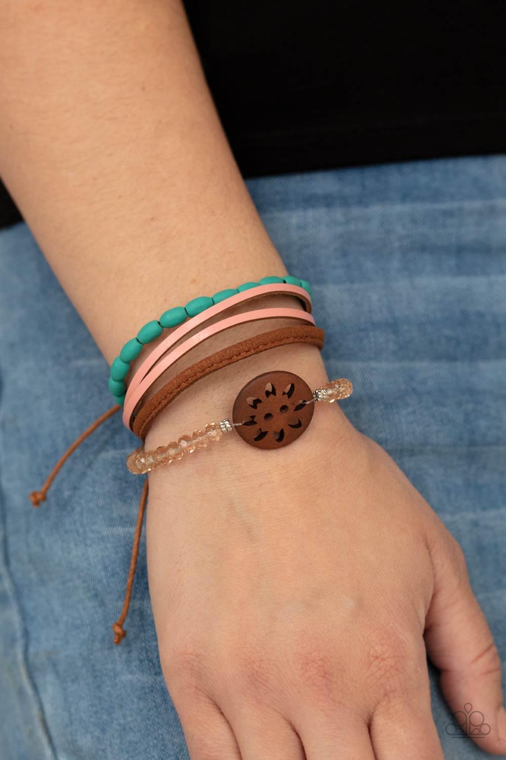 Paparazzi Accessories Desert Gallery - Blue Featuring a wooden floral centerpiece, mismatched strands of turquoise wooden beads, pink leather, brown suede, and topaz crystal-like beads layer across the wrist for a seasonal flair. Features an adjustable sl