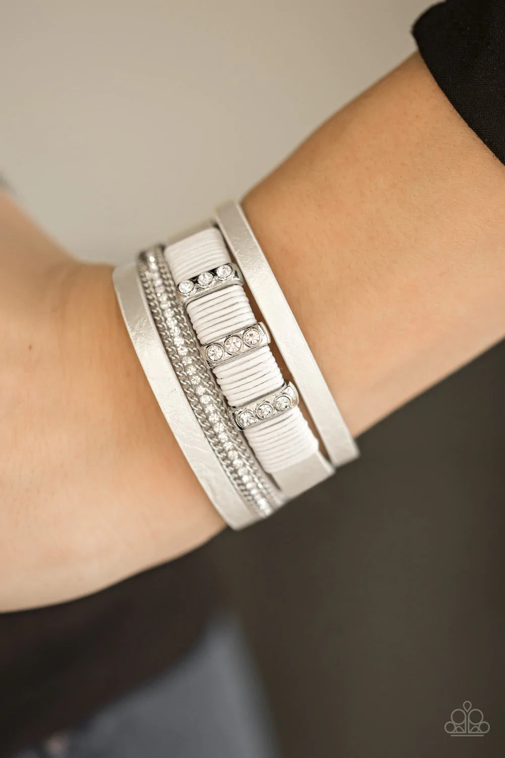 Paparazzi Accessories Frame Night - White Metallic white leather strands layer across the wrist. Infused with silver chain and white rhinestone accents, white cording knots around a leather strand, securing glittery white rhinestone frames in place for a