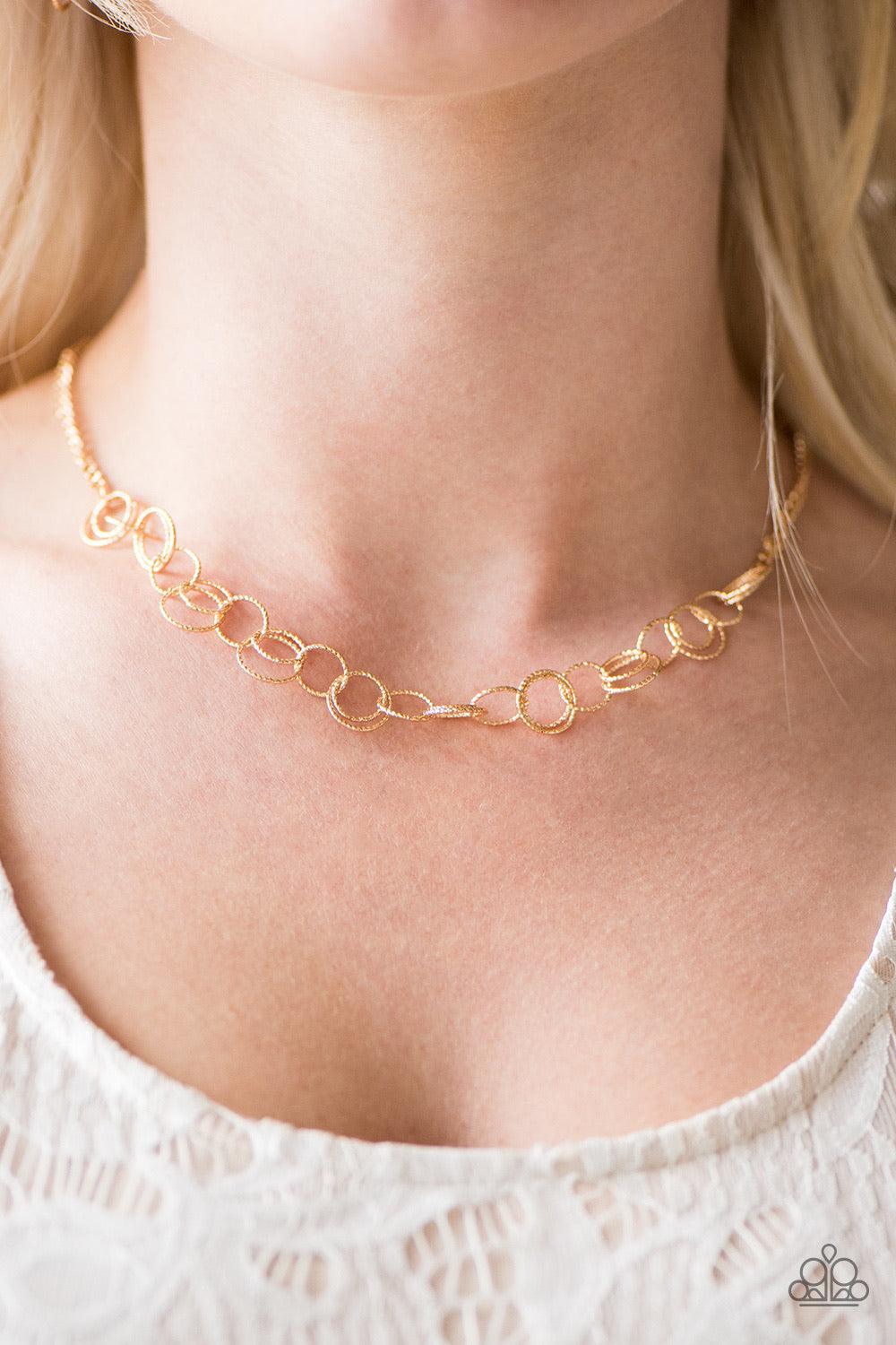 Paparazzi Accessories One Ring LEADS To Another - Gold Delicately etched in radiant textures, dainty gold rings join below the collar in a dizzying fashion. Features an adjustable clasp closure. Jewelry