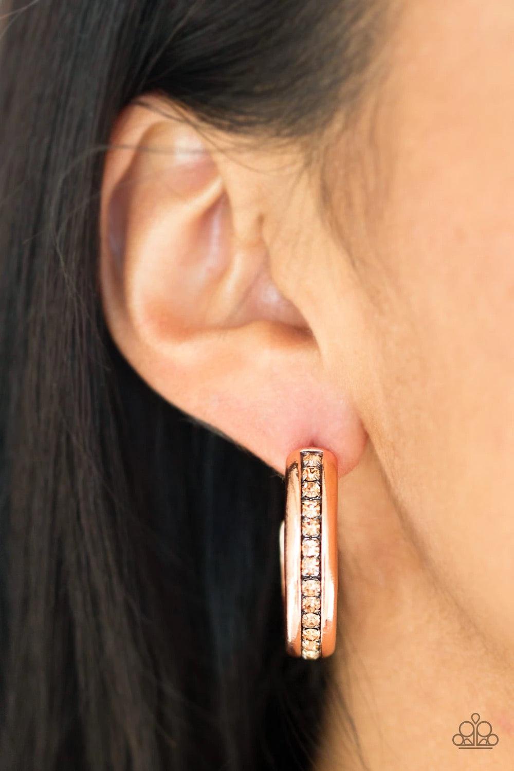 Paparazzi Accessories 5th Avenue Fashionista - Copper A row of glassy topaz rhinestones is encrusted down the spine of a shiny copper hoop for a refined look. Earring attaches to a standard post fitting. Hoop measures 1 1/4" in diameter. Sold as one pair