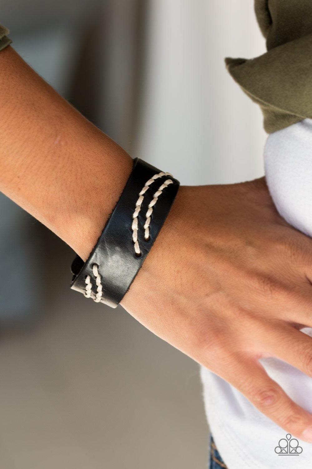 Paparazzi Accessories Rural Roamer - Black Sections of white cording is stitched across the front of a black leather band for a whimsical look. Features an adjustable snap closure. Jewelry