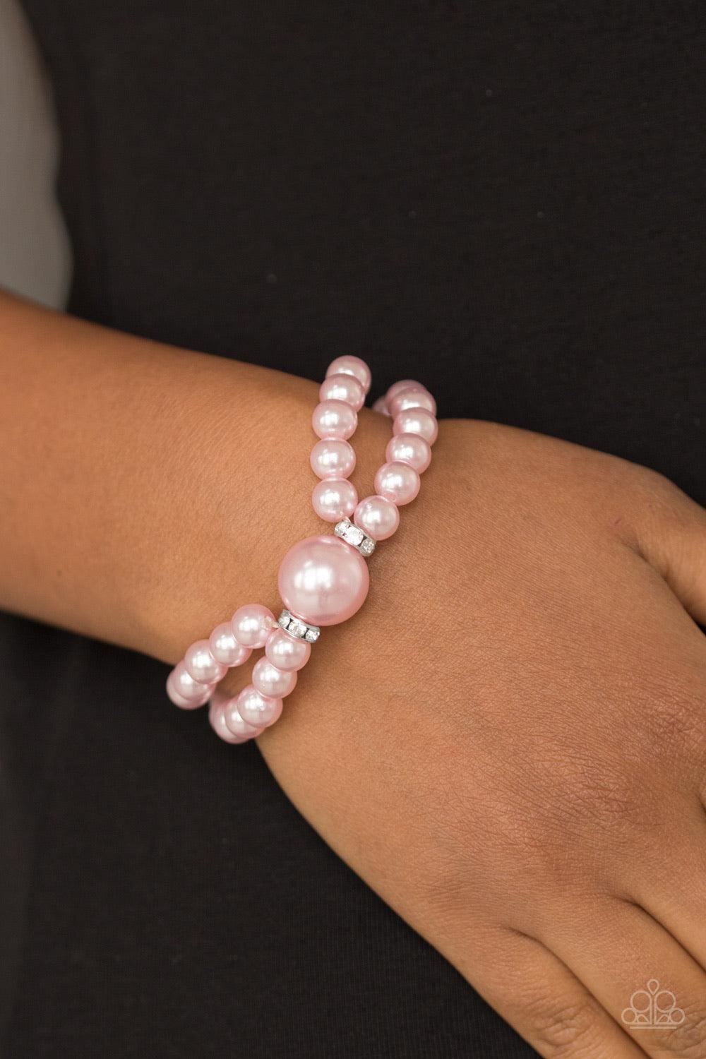 Paparazzi Accessories Romantic Redux - Pink Joined at the center by an oversized pink pearl and a pair of white rhinestone encrusted rings, classic pink pearls are threaded along stretchy bands around the wrist for a timelessly layered look. Jewelry