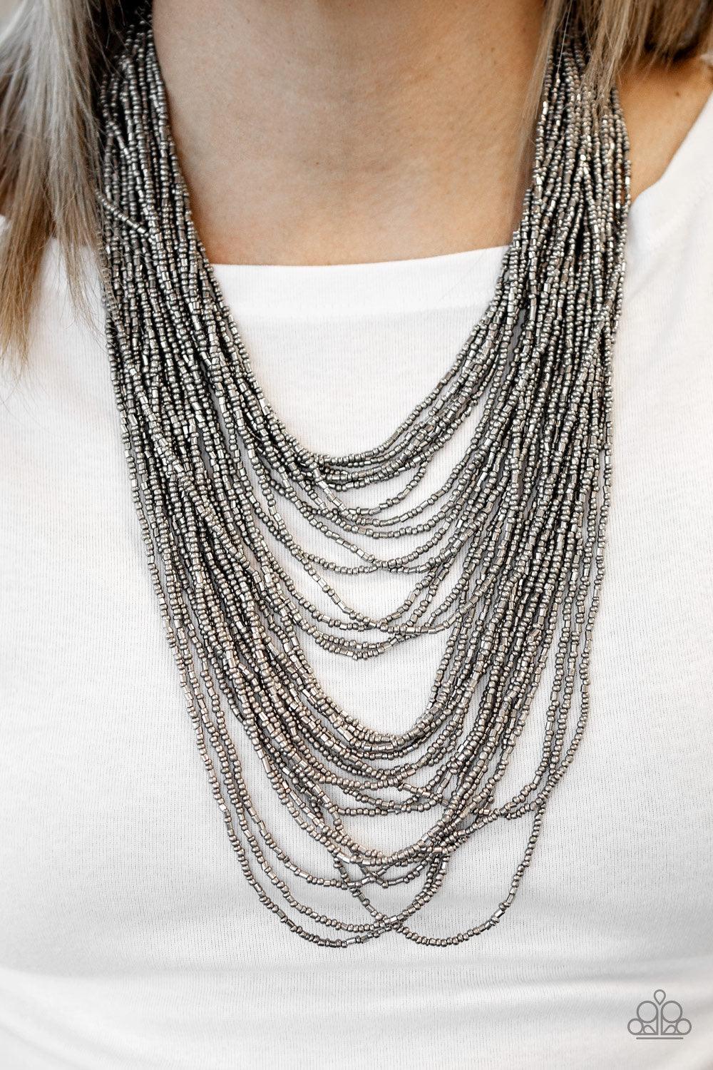 Paparazzi Accessories Dauntless Dazzle - Black Brushed in an icy metallic shimmer, countless strands of gunmetal seed beads drape across the chest in a bold fashion. Featuring a collision of shapes and shimmer, the glittery strands connect to two large gu