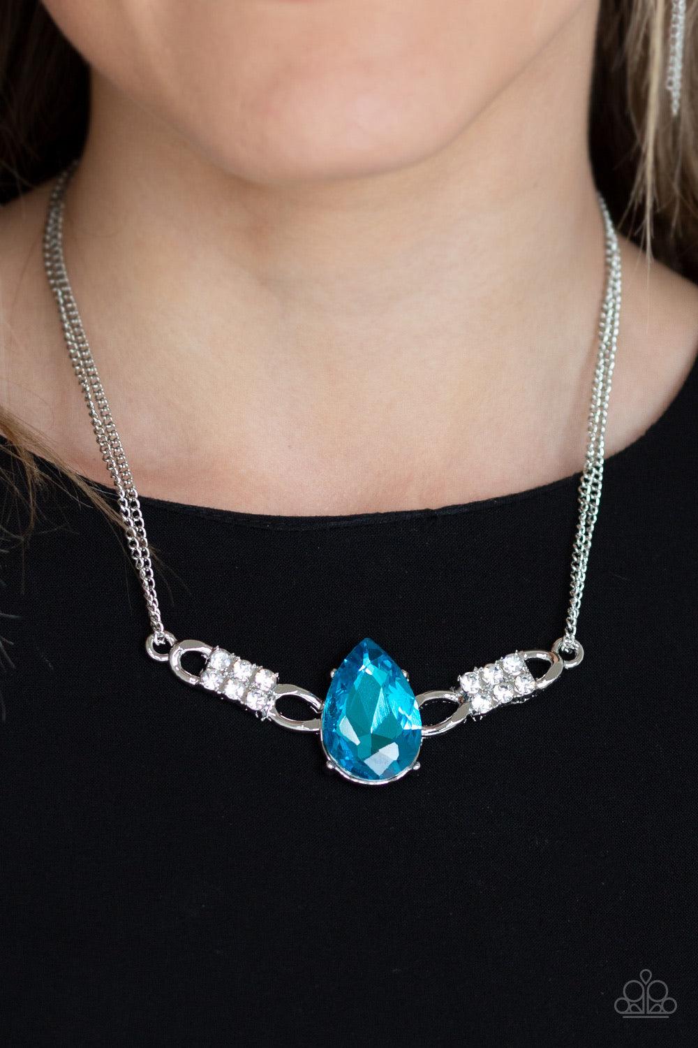 Paparazzi Accessories Way to Make An Entrance ~Blue Cut into an alluring teardrop, an oversized blue rhinestone gem attaches to bold silver frames radiating with glassy white rhinestones. The dramatic pendant attaches to doubled silver chains, swinging ho