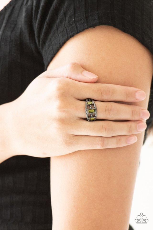 Paparazzi Accessories Noble Nova - Green Three green emerald-cut rhinestones are encrusted along three gunmetal bands radiating with smooth surfaces and sections of glittery hematite rhinestones for an edgy fashion. Features a stretchy band for a flexible