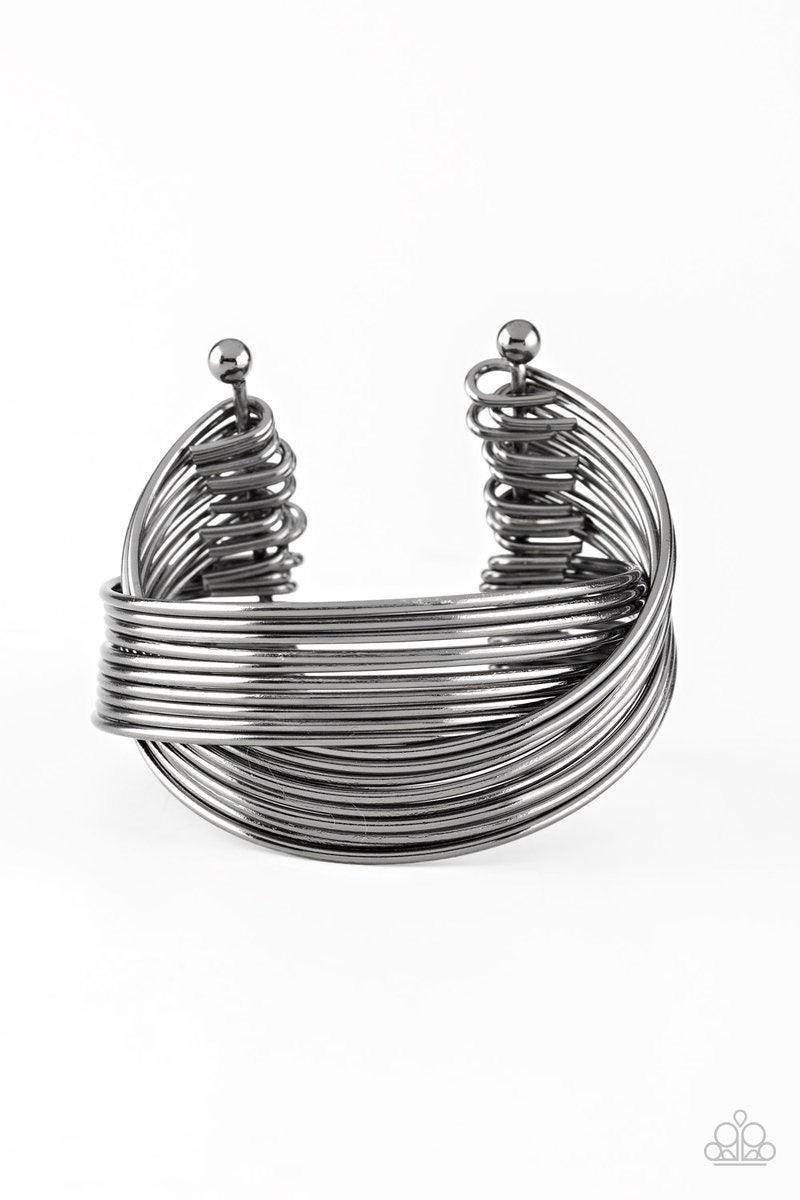 Paparazzi Accessories Urban Glam ~Black Threaded along two metallic rods, glistening gunmetal bars crisscross across the wrist, coalescing into a layered cuff.