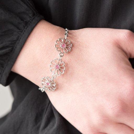 Paparazzi Accessories Dancing Daffodils - Pink Stenciled silver floral charms link around the wrist. Glittery pink rhinestones dot the dainty floral centers, adding a whimsical finish to the airy palette. Features an adjustable clasp closure. Sold as one