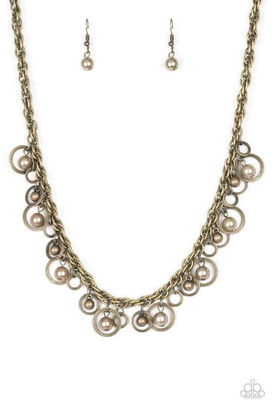 Paparazzi Accessories Shipwreck Style - Brass Brushed in an antiqued shimmer, mismatched brass hoops, brass pearls, and dainty brass beads swing from the bottom of a bold brass chain below the collar for a refined look. Features an adjustable clasp closur