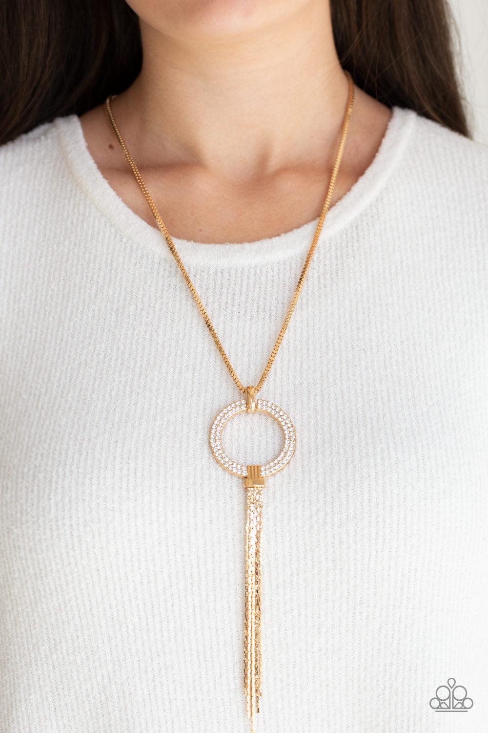 Paparazzi Accessories Not A HEIR Out Of Place - Gold Encrusted in blinding white rhinestones, a sparkling gold ring swings from the bottom of a lengthened gold box chain. Flattened gold chains stream from the bottom of the glittery pendant for a regal fin