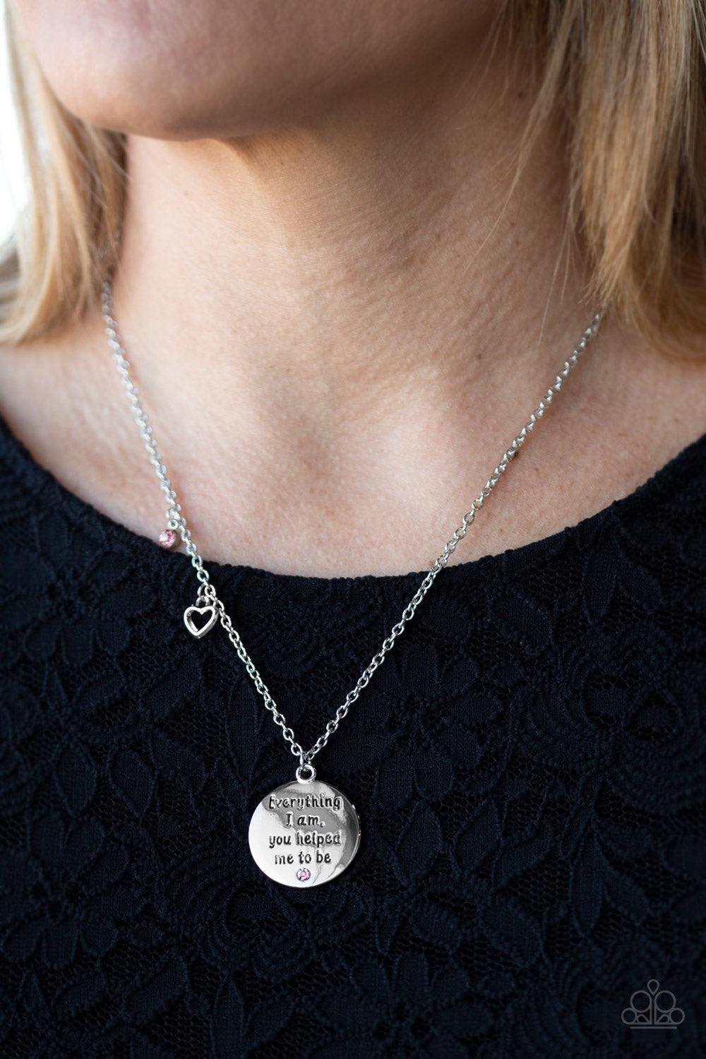 Paparazzi Accessories Everything I Am - Pink A solitaire pink rhinestone, dainty silver heart, and a shimmery silver disc stamped with the inspirational phrase, "Everything I am, you helped me to be", swings below the collar for a whimsical look. Features