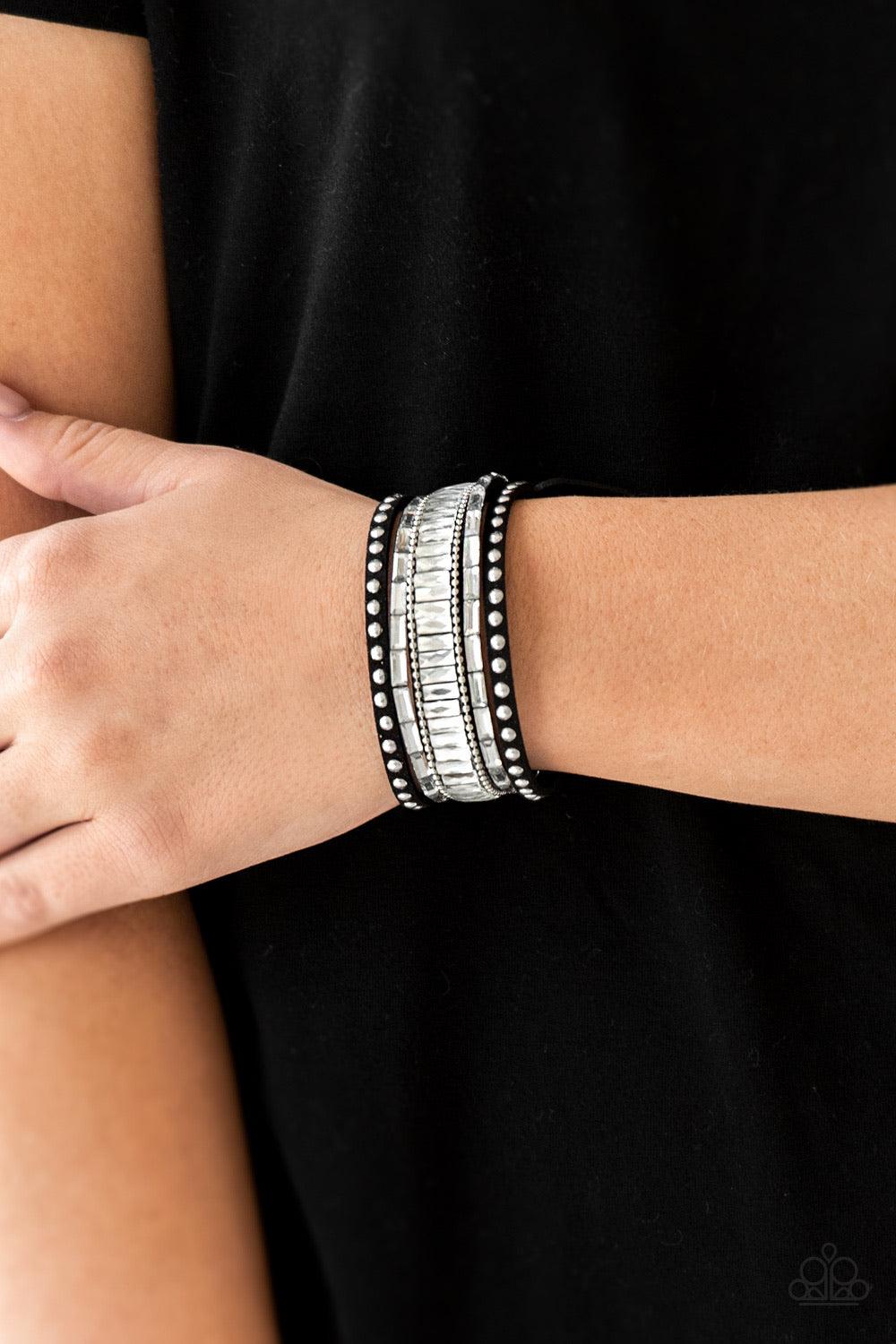 Paparazzi Accessories Rock Star Rocker - Black Shiny silver studs, dainty silver ball chains, and edgy white emerald-cut rhinestones race along a spliced black suede band for a rock star look. Features an adjustable snap closure. Sold as one individual br