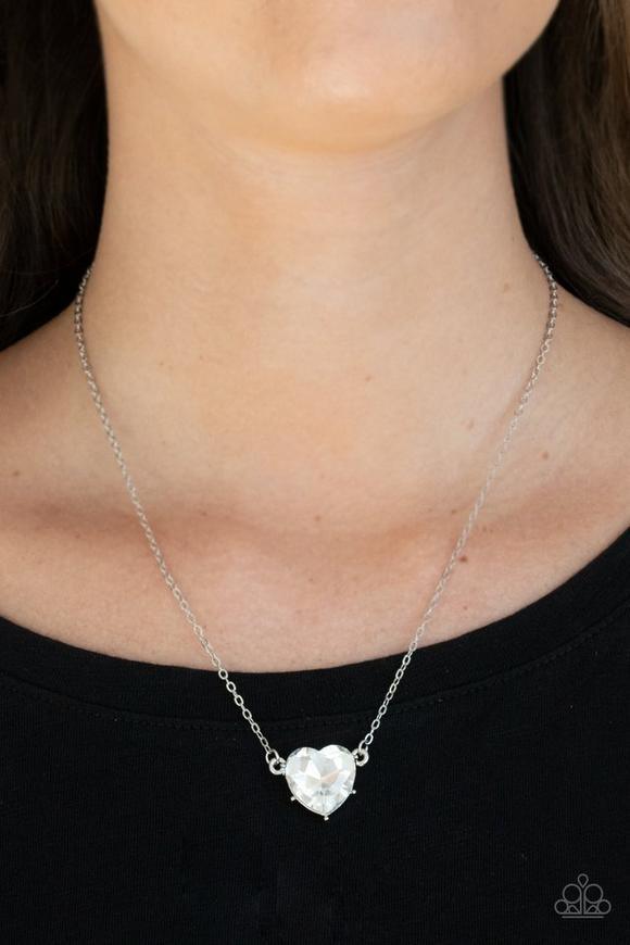 Paparazzi Accessories She Works HEART for the Money - White Cut into a flirtatious heart shape, a dramatically oversized white rhinestone pendant swings from the bottom of a dainty silver chain below the collar for a glamorous finish. Features an adjustab