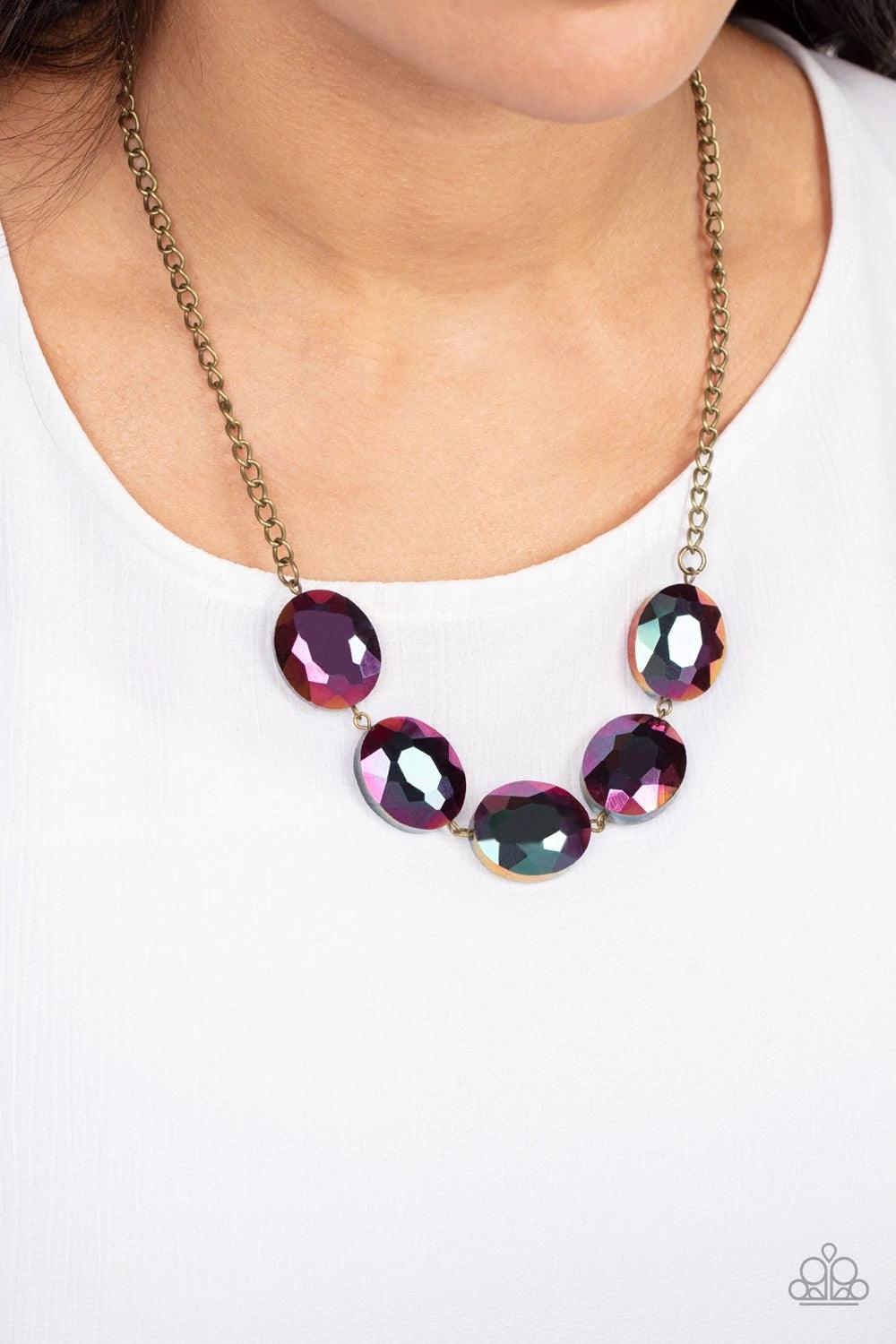 Paparazzi Accessories Cosmic Closeup - Brass Dipped in a metallic oil spill finish, a faceted collection of oversized iridescent gems delicately links below the collar for a gritty glamorous look. Features an adjustable clasp closure. Sold as one individu