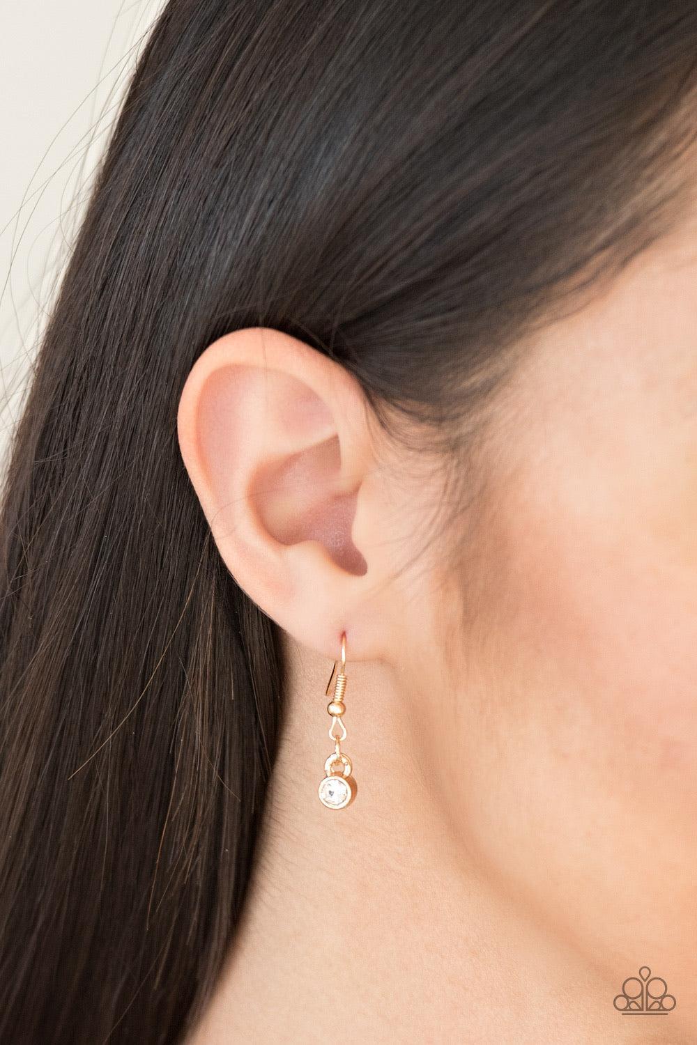 Paparazzi Accessories Here We GLOW! - Gold Gradually increasing in size towards the center, glittery white rhinestones link across the bottom of an elegantly elongated gold chain for a timeless look. Features an adjustable clasp closure. Jewelry