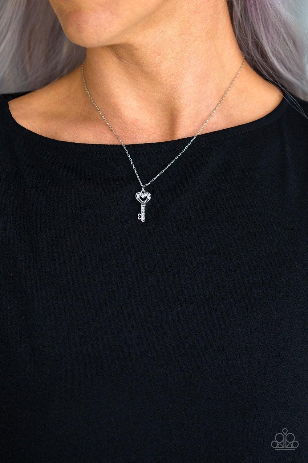 Paparazzi Accessories Lock Up Your Valuables - White Dotted in glassy white rhinestones, a dainty silver key pendant swings below the collar for a charming look. Features an adjustable clasp closure. Jewelry