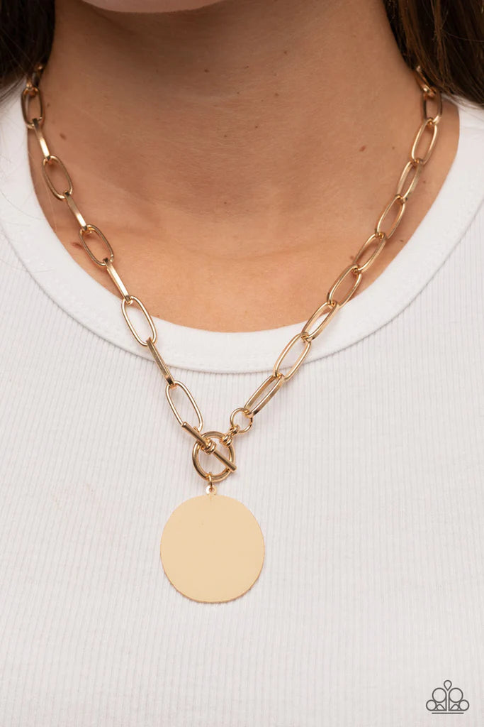 Paparazzi Accessories Tag Out - Gold An oversized oval gold disc swings from the bottom of a substantial oval linked gold chain, resulting in a gritty industrial pendant below the collar. Features a toggle closure. Sold as one individual necklace. Include