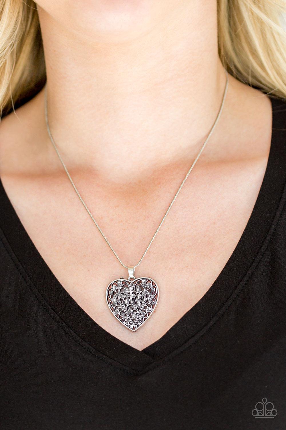 Paparazzi Accessories Look Into Your Heart - Silver Filled with vine-like filigree detail, a silver heart pendant swings below the collar for a vintage inspired look. Features an adjustable clasp closure. Sold as one individual necklace. Includes one pair