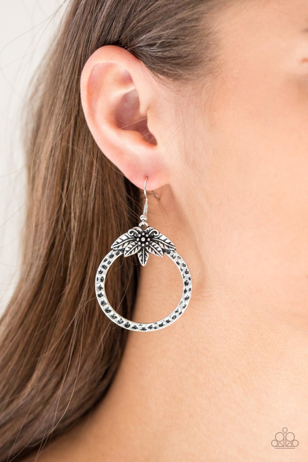 Paparazzi Accessories Island Insider - Silver Featuring lifelike details, a flowery frame blooms across the top of a hammered silver hoop for a seasonal look. Earring attaches to a standard fishhook fitting. Jewelry