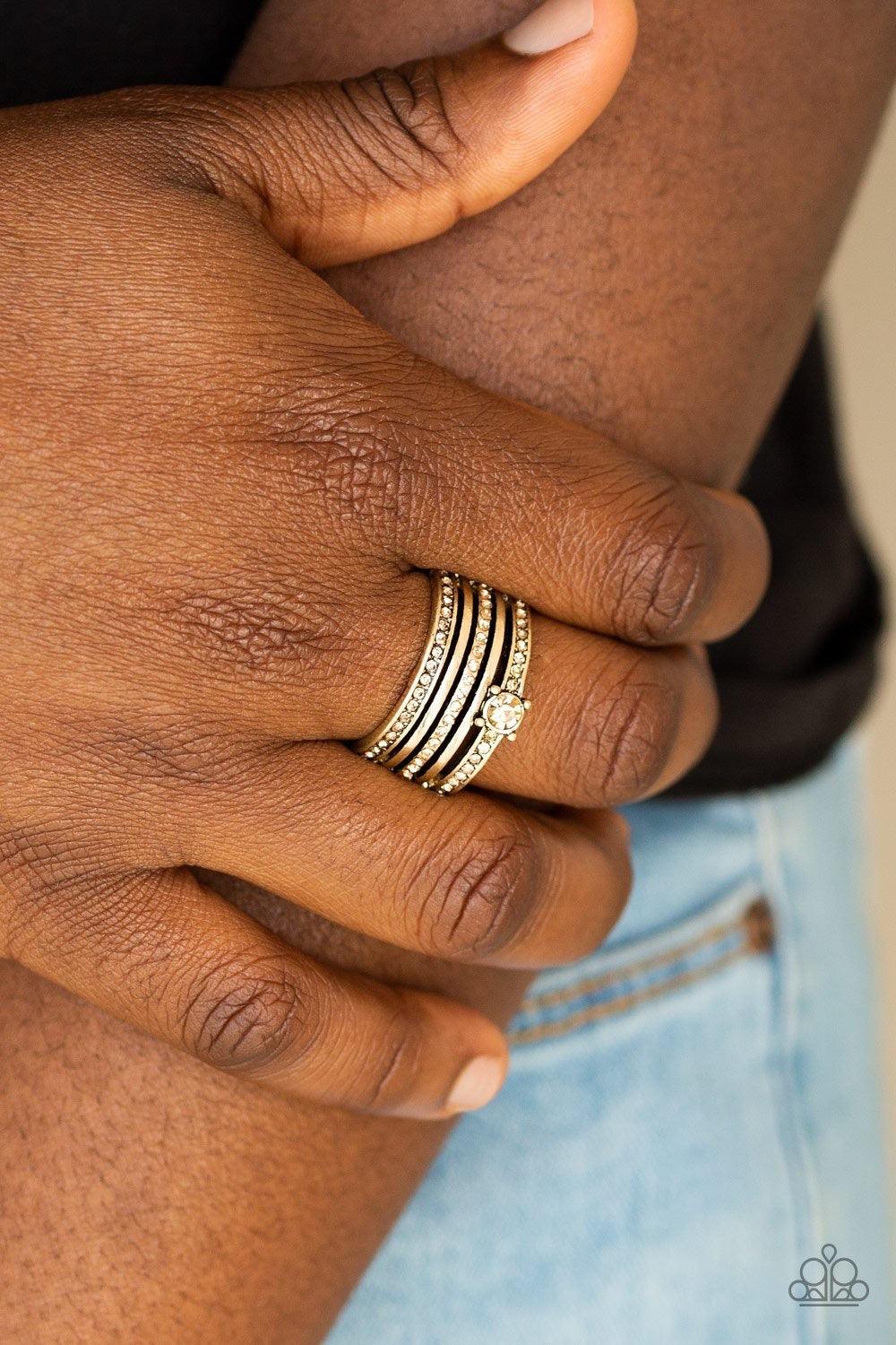 Paparazzi Accessories The Dealmaker - Brass Encrusted in golden topaz rhinestones, glittery bands alternate with shiny brass bands across the finger. A slightly larger rhinestone adorns the uppermost band for a refined finish. Features a stretchy band for