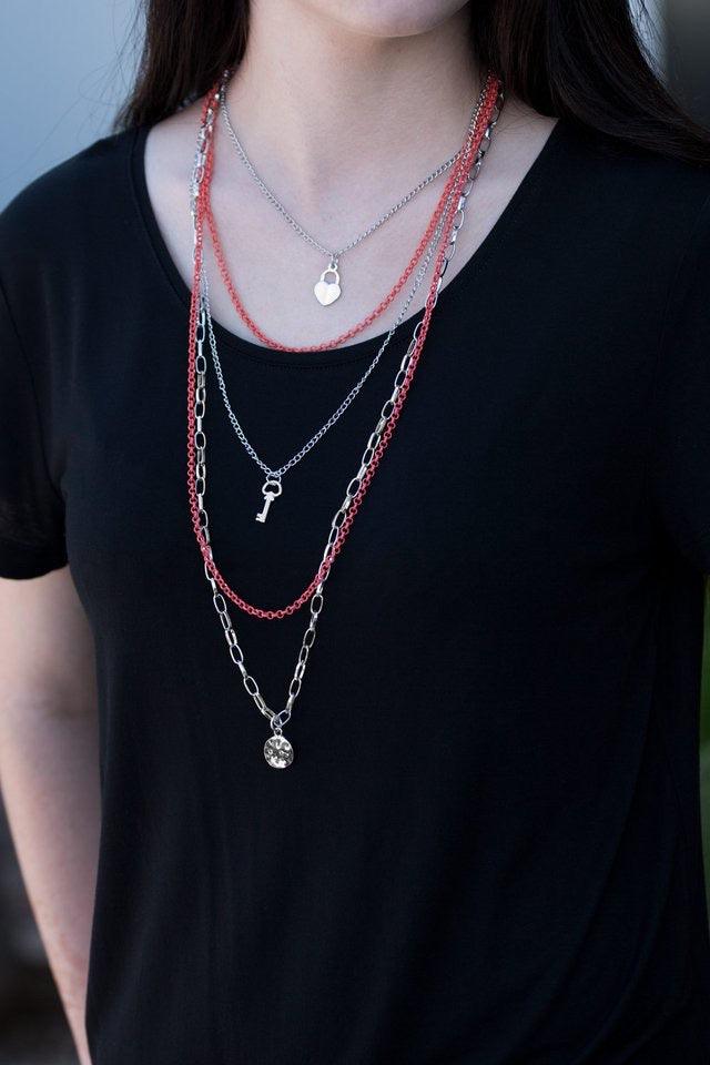 Paparazzi Accessories Right On Key - Orange Layers of orange and silver chain fall together to create the illusion of five separate necklaces. Each silver chain is adorned with a small silver charm, including a heart and a key. Features an adjustable clas