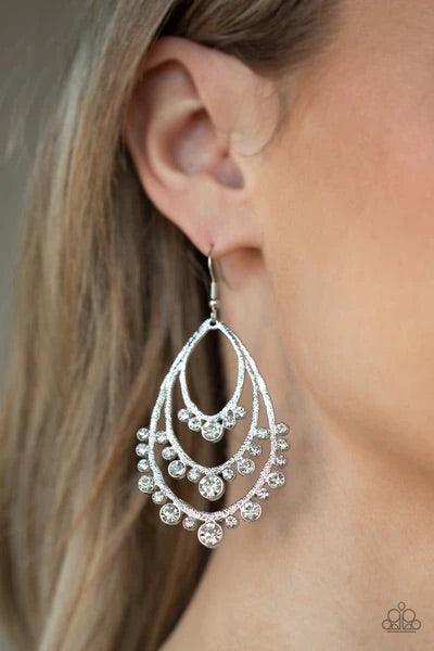 Paparazzi Accessories Break Out In TIERS - White A gorgeous collection of glassy white rhinestones drip from the bottom of a tiered silver frame, coalescing into a dazzling statement piece. Earring attaches to a standard fishhook fitting. Sold as one pair