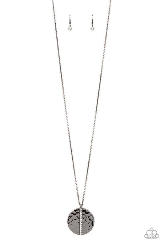 Paparazzi Accessories Token of My Gratitude - Black An icy row of glittering white rhinestones is pressed into the center of a hammered gunmetal disc, splitting the oversized pendant seemingly in two as it swings from the bottom of an extended gunmetal ch