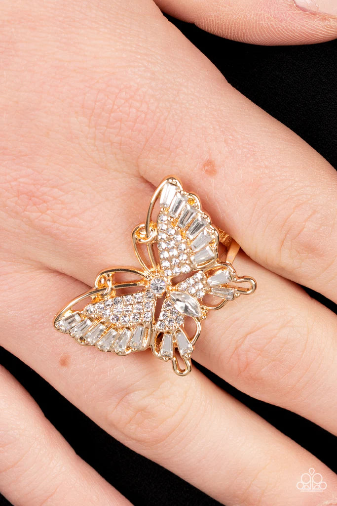 Paparazzi Accessories Fearless Flutter - Gold Sparkling with round, teardrop, and emerald cut white rhinestones, a gold butterfly fearlessly flutters atop the finger for a statement-making finish. Features a stretchy band for a flexible fit. Sold as one i