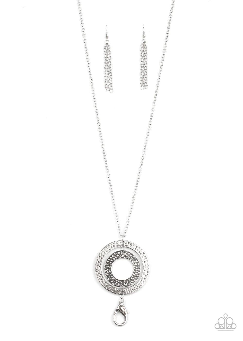 Paparazzi Accessories Circle Back To That - Silver Featuring hammered finishes, two asymmetrical silver rings dangle from the bottom of a lengthened silver chain for a rustic look. A lobster clasp hangs from the bottom of the design to allow a name badge