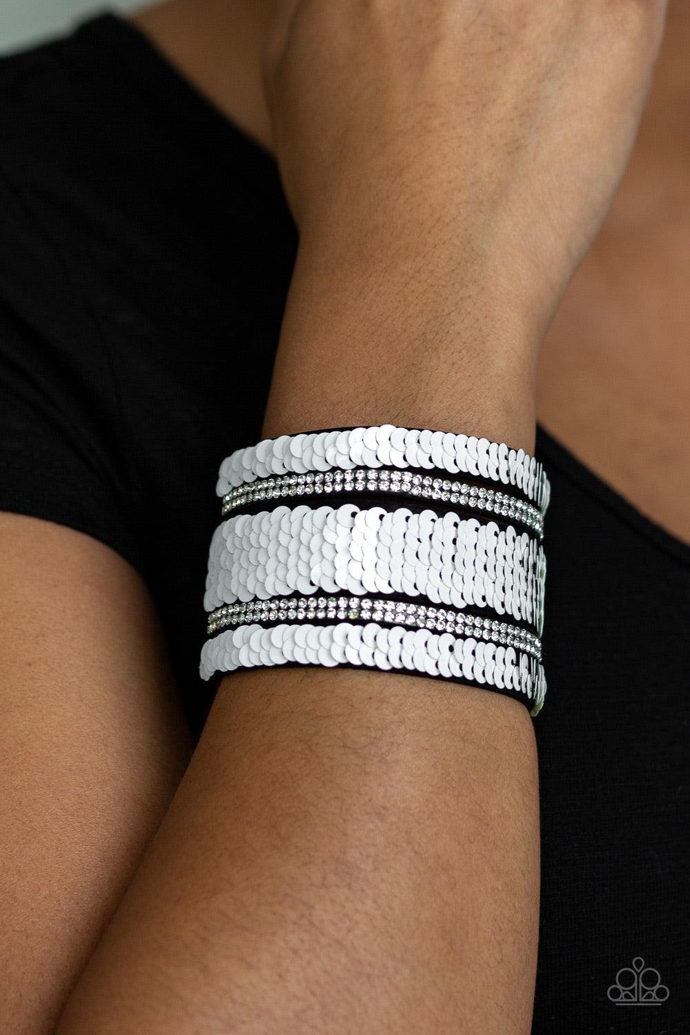 Paparazzi Accessories MERMAID Service - White Infused with strands of blinding white rhinestones, row after row of shimmery sequins are stitched across the front of a spliced black suede band. Bracelet features reversible sequins that change from white to
