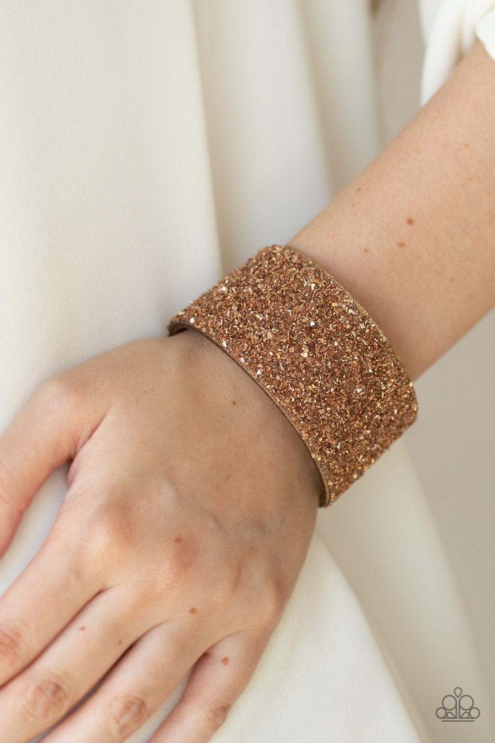 Paparazzi Accessories The Halftime Show - Gold Crushed bits of rose gold accents are sprinkled along the center of a glittery suede band, creating a blinding shimmer around the wrist. Features an adjustable snap closure. Jewelry
