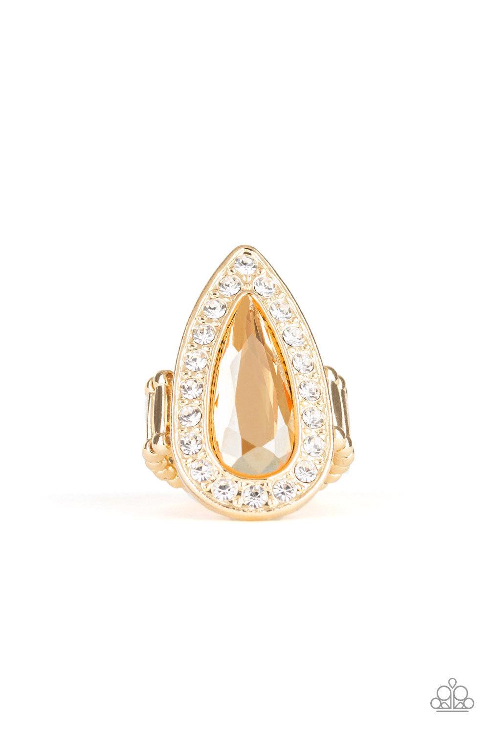 Paparazzi Accessories Majestic Mayhem ~Gold An oversized golden teardrop gem is pressed in the center of a glistening gold teardrop frame radiating with glassy white rhinestones for a fierce look. Features a stretchy band for a flexible fit.